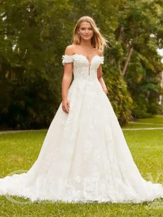 Model is wearing an off the shoulder a-line wedding dress with a plunging neckline and lace fabric