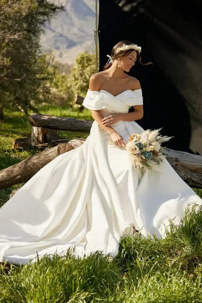model is wearing a romantic off the shoulder ball gown wedding dress