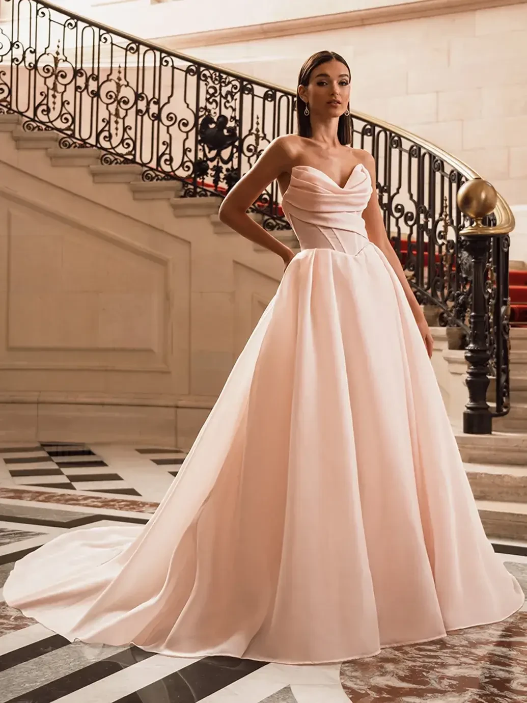 model is wearing a strapless blush organza ball gown